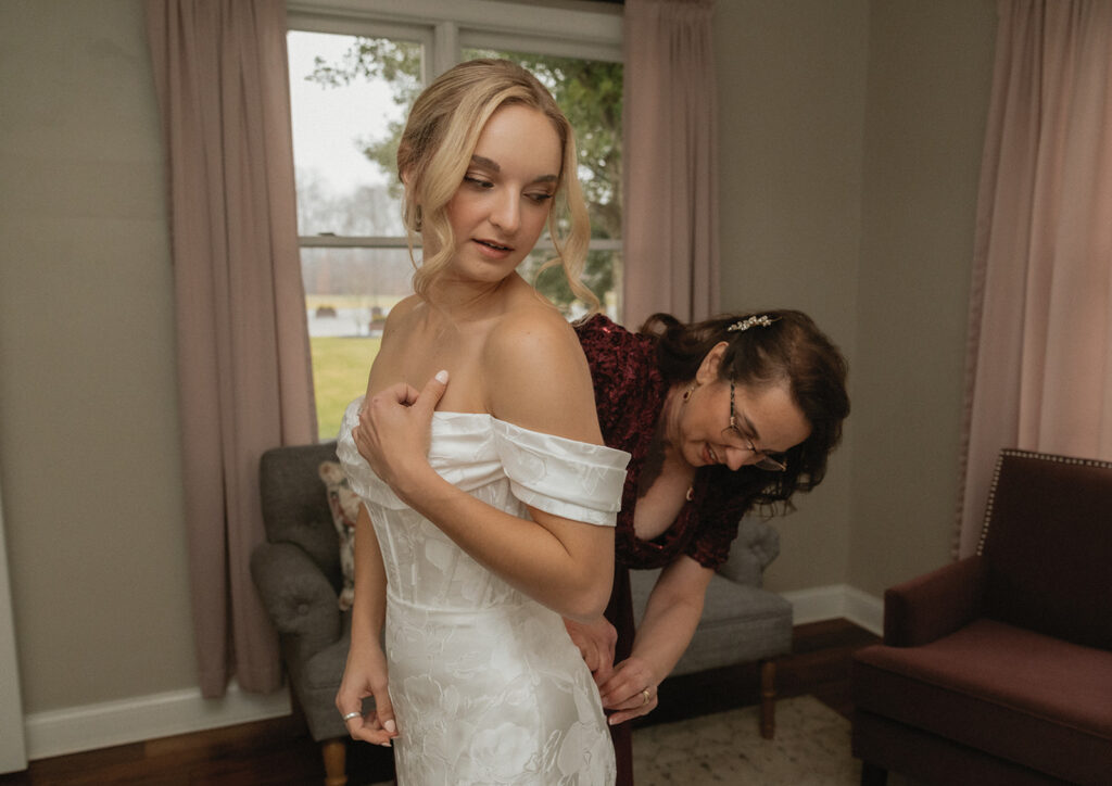 bride's mother helping her get dressed